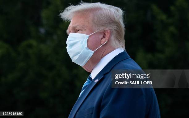 President Donald Trump wears a facemask as he leaves Walter Reed Medical Center in Bethesda, Maryland heading to Marine One on October 5 to return to...