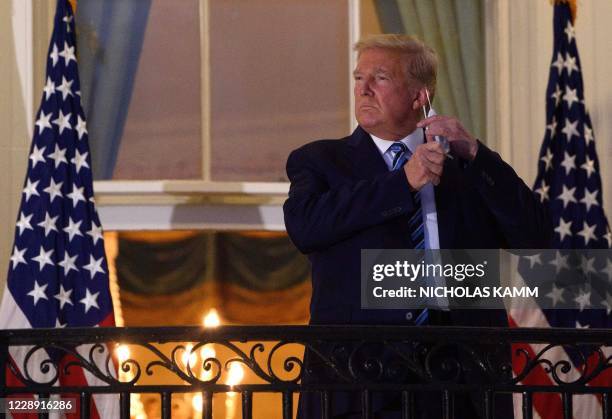 President Donald Trump takes off his facemask as he arrives at the White House upon his return from Walter Reed Medical Center, where he underwent...