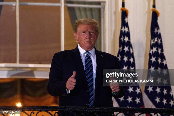 President Donald Trump gives two thumbs up from the Truman Balcony upon his return to the White House from Walter Reed Medical Center, where he...