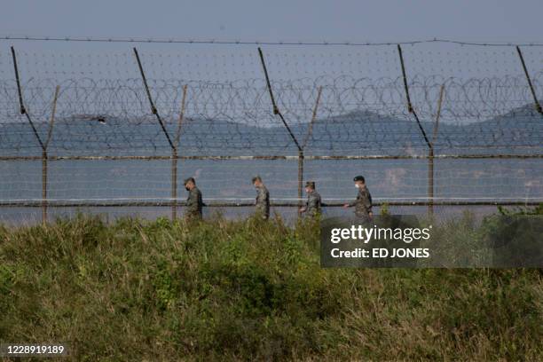 South Korean soldiers walk along a fence of the Demilitarized Zone separating North and South Korea, on the South Korean island of Gyodong on October...