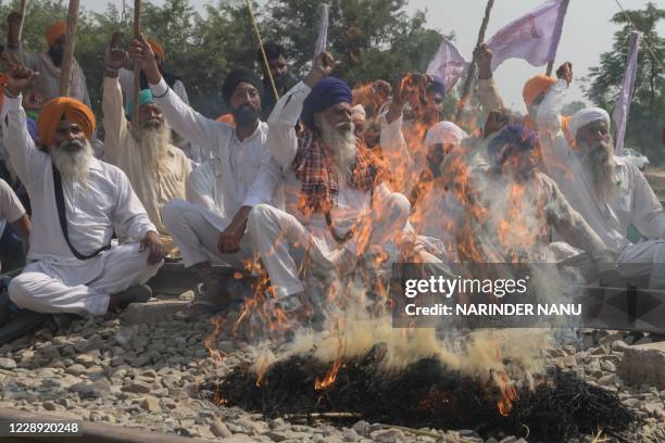 Farmers shout slogans while burning an effigy with pictures of Congress party leader Rahul Gandhi, Indian Prime Minister Narendra Modi, Aam Aadmi...