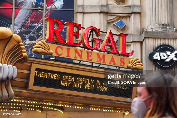 Woman wearing a face mask walks past the Regal Cinemas. Regal Cinemas which is the second-largest operator of theatres in the United States, plans to...