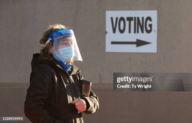 An early voter, wearing a mask and a face shield, stands in line waiting to register for early voting outside of the Franklin County Board of...