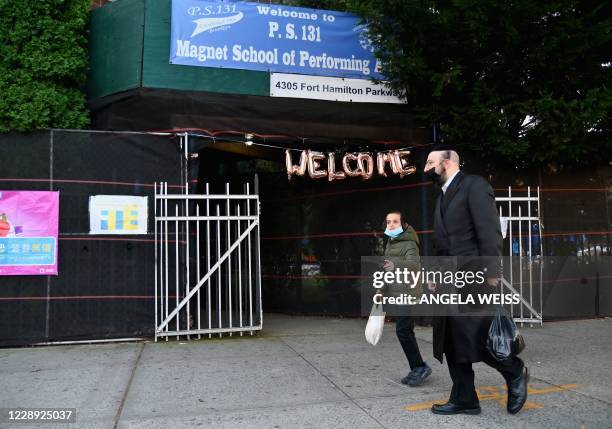 Hasidic males with facemasks, walk past a closed public school in the Brooklyn neighborhood of Borough Park on October 6, 2020 in New York City. -...