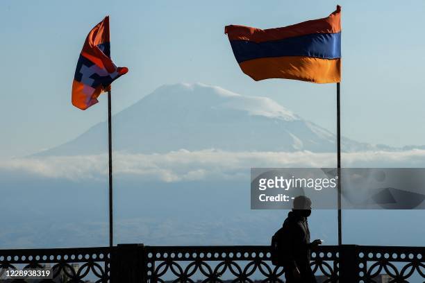 Man walks on a bridge decorated with flags of Armenia and the breakaway Nagorno-Karabakh region, with Mount Ararat on the background, in Yerevan on...