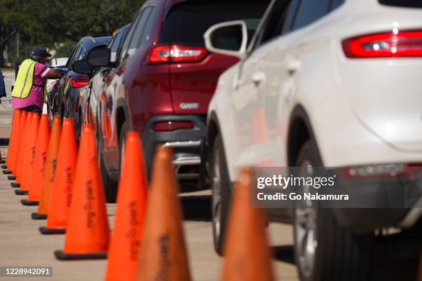 An election worker accepts ballots from voters in cars at a drive-through mail ballot drop-off site at NRG Stadium on October 7, 2020 in Houston,...