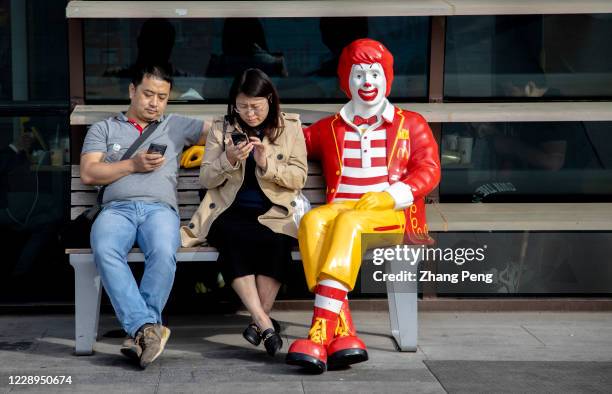 Customers rest beside the statue of Ronald McDonald outside a McDonald's restaurant. Since the epidemic situation of COVID-19 had been controlled...