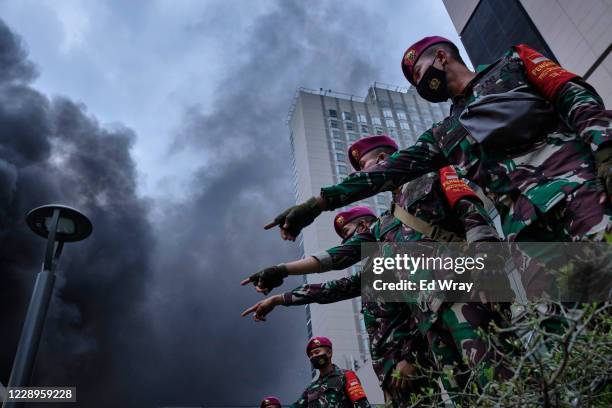 Indonesian soldiers point to rioters destroying a bus station on the main street in the centre of the city on October 8, 2020 in Jakarta, Indonesia....