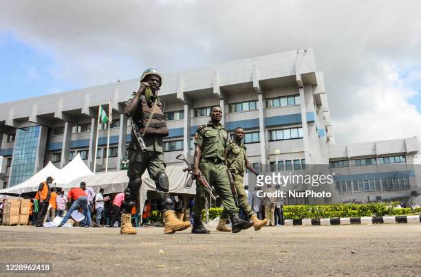 Police officers walk pass officials The Independent National Electoral Commission while distributing the electoral sensitive materials to various...
