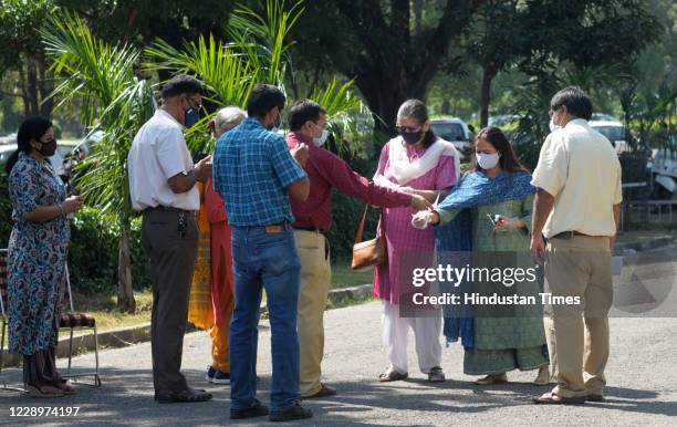 Faculty members sanitize their hands before heading to vote in the Panjab University Teachers Association election at English Auditorium inside...