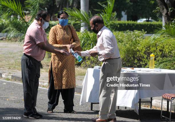 Faculty members sanitize their hands before heading to vote in the Panjab University Teachers Association election at English Auditorium inside...