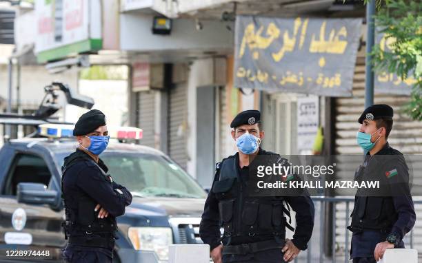 Mask-clad Jordanian policemen man a checkpoint as they enforce a COVID-19 coronavirus lockdown in the capital Amman on October 9, 2020.