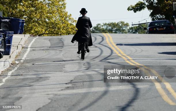 Member of the Orthodox Jewish community rides a bicycle in the town of Monsey in New York's Rockland County, on October 9, 2020. - New restrictions...