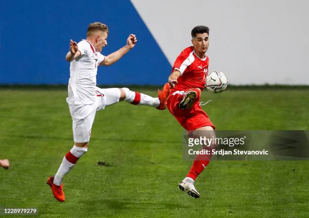 Zeljko Gavric of Serbia competes for the ball against Mateusz Bogusz of Poland during the EURO U21 qualifying match between Serbia U21 and Poland U21...