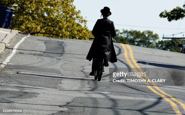 Member of the Orthodox Jewish community rides a bicycle in the town of Monsey in New York's Rockland County, on October 9, 2020. - New restrictions...