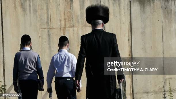 Members of the Orthodox Jewish community walk in the town of Monsey in New York's Rockland County, on October 9, 2020. - New restrictions are in...