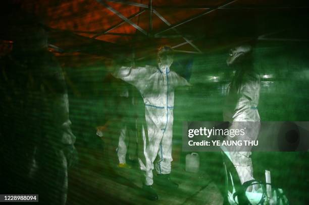 This photo taken on October 9, 2020 show volunteers wearing personal protective equipment as they disinfect themselves after the transfer of people...