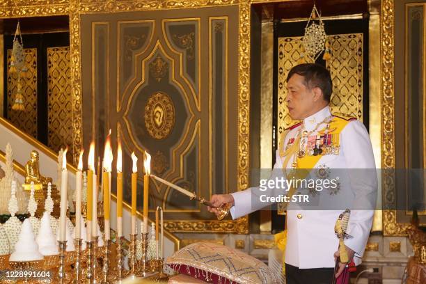 Thailand's King Maha Vajiralongkorn lights candles as he takes part in a Buddhist ceremony to mark the 2020 Kathina festival at Wat Ratchabophit in...