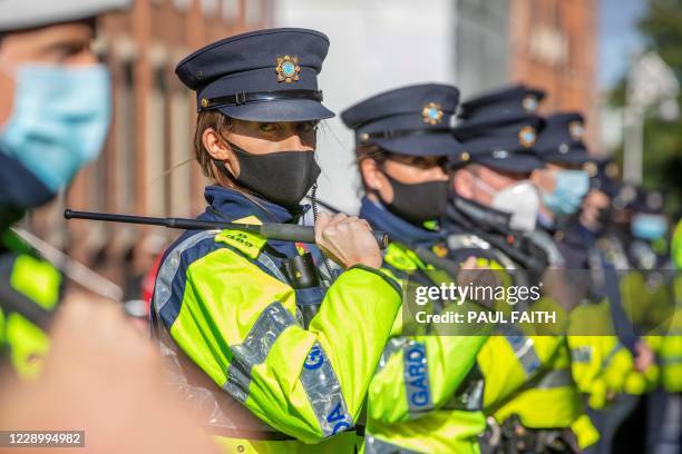 Garda stand with batons drawn to keep counter-protestors from protestors staging a demonstration against the Irish government imposed restrictions...