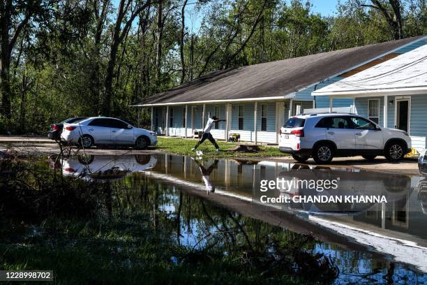 Man jumps over flooded water outside his house after Hurricane Delta passed through the area on October 10, 2020 near Lake Charles, Louisiana. -...
