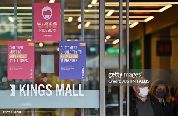 Shoppers wearing face masks as a precaution against the transmission of the novel coronavirus leave a shopping mall in west London on October 11,...