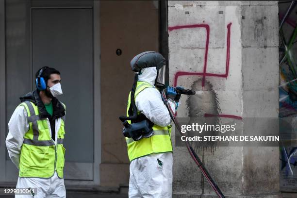 Municipal worker cleans swastikas spray painted on columns of the Rivoli street in central Paris on October 11, 2020.