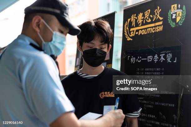 Police officer takes down the identification of a media staff during the Hong Kong Protest exhibition. A road tour photo exhibition organised by a...