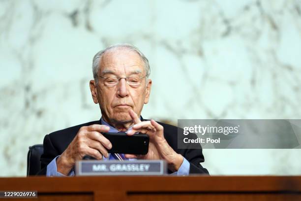 Sen. Chuck Grassley , uses his phone during Supreme Court Justice nominee Judge Amy Coney Barrett's Senate Judiciary Committee confirmation hearing...