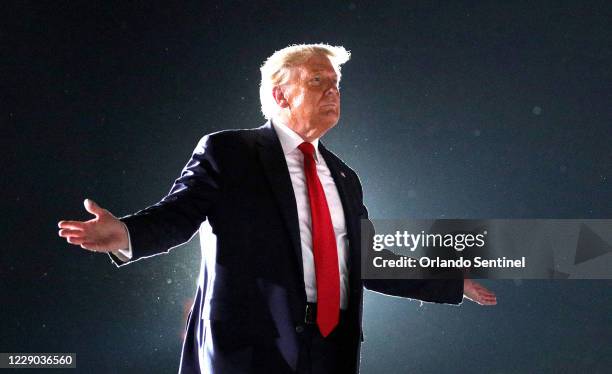 President Donald Trump waves goodbye to cheering supporters as he departs his campaign rally at Orlando Sanford International Airport in Sanford,...