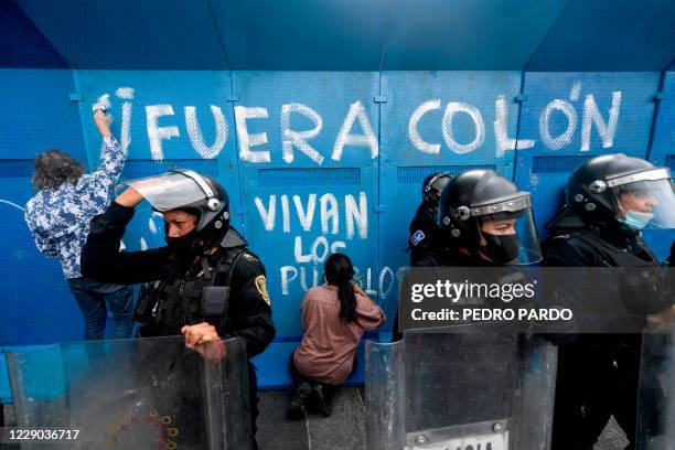 Demonstrators make a graffiti reading "Colon Out, Long Live the Peoples" on a metal fence surrounding a statue of Christopher Columbus for...