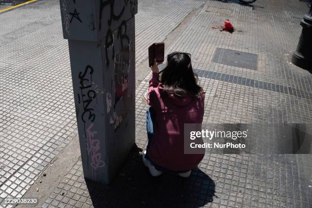 Woman protects herself from the police car, while recording the clashes with her cell phone during a protest in the framework of the Day of the Race,...