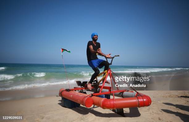 Palestinian youth Muhammad Al-Radi poses before the test ride of his pedal boat, which he made from scrap iron and plastic during the lockdown...