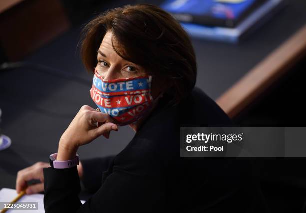 Sen. Amy Klobuchar wears a face mask that reads "Vote" while Supreme Court nominee Judge Amy Coney Barrett testifies before the Senate Judiciary...