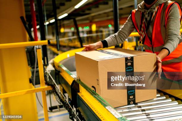 Worker collects an Amazon Prime customer order package from a conveyor at an Amazon.com Inc. Fulfillment center in Frankenthal, Germany, on Tuesday,...