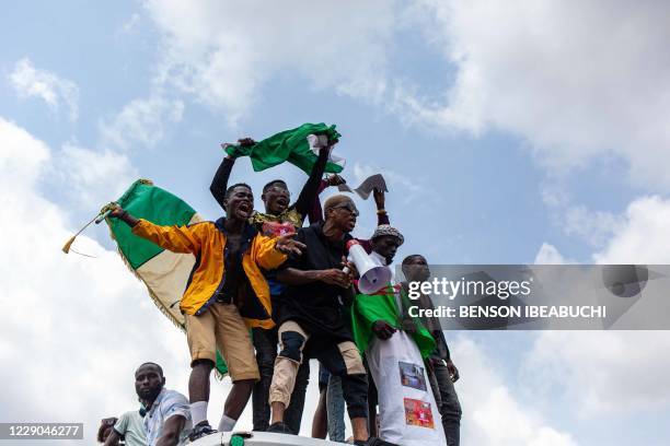 Nigerian youths seen waving the Nigerian national flag in front of a crowd in support of the ongoing protest against the unjust brutality of The...