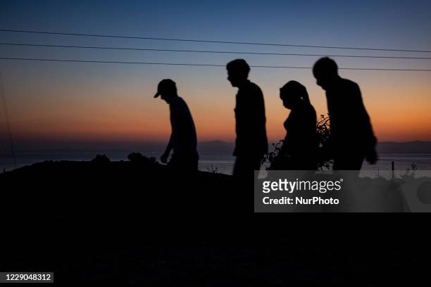 Silhouettes of walking refugees and migrants on the hills early in the morning during the dawn and the sunrise over the Aegean sea and Turkey. Asylum...