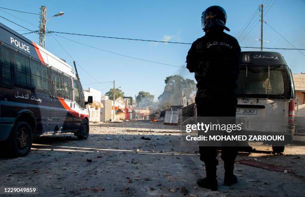 Tunisian security forces stand guard as protesters take to the streets of the impoverished Tunisian town of Sbeitla on October 13, 2020 after a man...