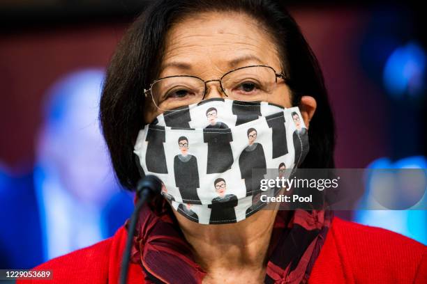 Sen. Mazie Hirono wears a face mask depicting illustrations of Justice Ruth Bader Ginsburg as Supreme Court nominee Judge Amy Coney Barrett testifies...