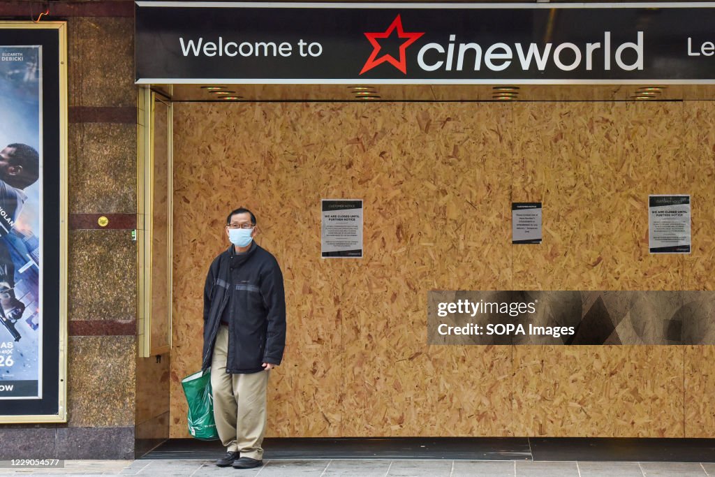 A man wearing a face mask stands outside the Cineworld...