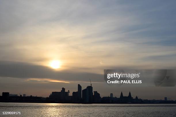 The sun rises across the River Mersey and the Liverpool skyline in north west England on October 14, 2020. - The government announced further...