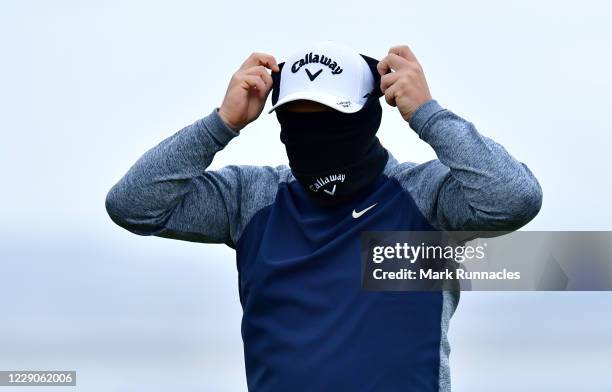 Callum Shinkwin of England plays hid and seek with his snood at the 18th green during previews at the Scottish Championship presented by AXA at...