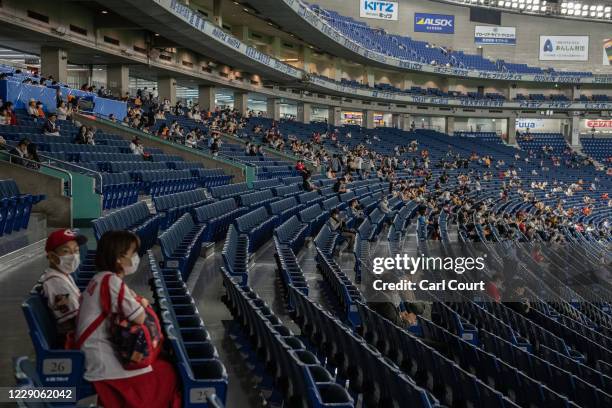 Fans sit in socially distanced seats as they wait to watch the Japan Central League baseball match between Yomiuri Giants and Hiroshima Carp at Tokyo...