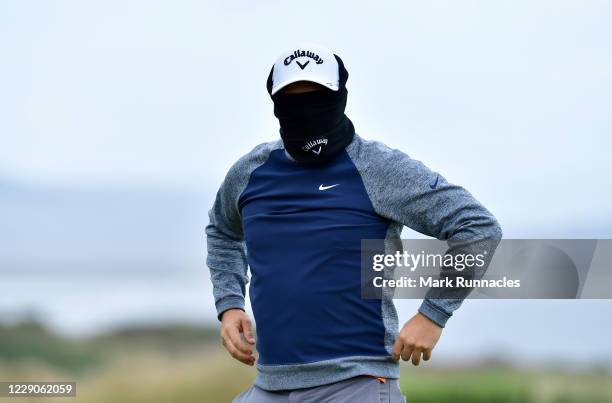 Callum Shinkwin of England plays hid and seek with his snood at the 18th green during previews at the Scottish Championship presented by AXA at...