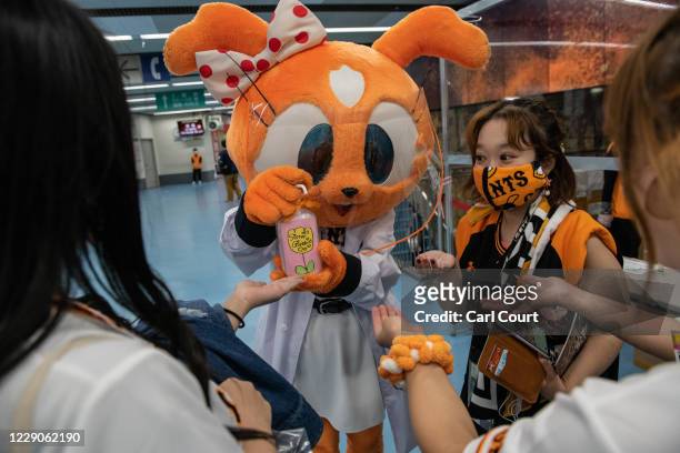 Yomiuri Giants mascot wearing a plastic visor sprays hand sanitiser onto the hands of fans at Tokyo Dome ahead of the Japan Central League baseball...