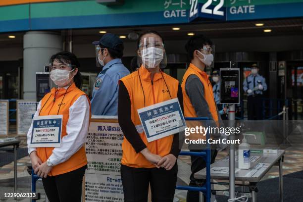 Stewards wearing face masks and plastic visors wait to check the temperature of fans arriving at Tokyo Dome ahead of the Japan Central League...