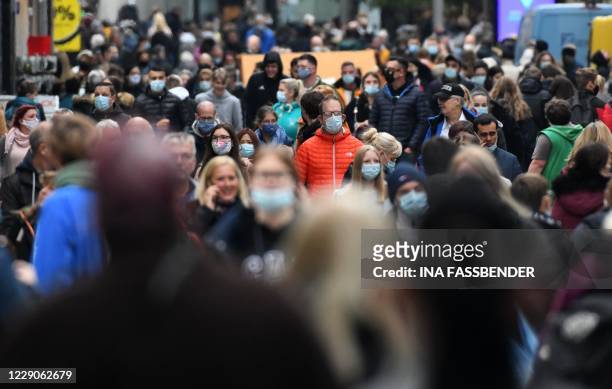 People wearing protective face masks walk in the pedestrian area in the city of Dortmund, western Germany, on October 14 amid the ongoing novel...