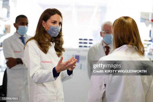 Britain's Catherine, Duchess of Cambridge, talks with staff as she tours a laboratory wearing a face mask as a precaution against the transmission of...