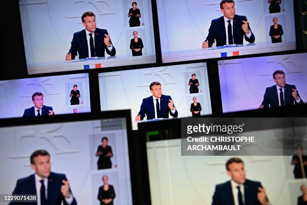 This picture shows screens displaying French President Emmanuel Macron as he addresses the nation during a televised interview from the Elysee Palace...