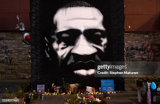 Candles are placed beneath a portrait of George Floyd during a birthday celebration for him at a memorial site known as "George Floyd Square" on...