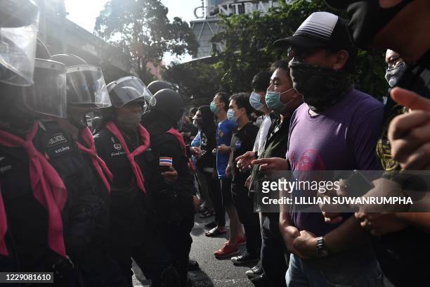 Phalanx of police and pro-democracy protesters face off during a rally on a traffic intersection in Bangkok on October 15 after Thailand issued an...